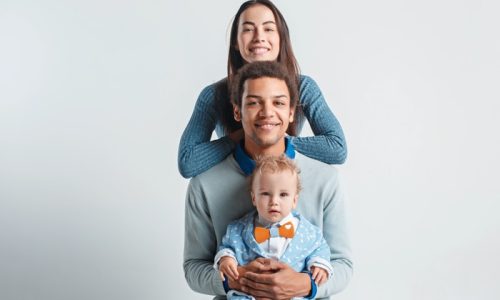 A happy family of afro man and caucasian woman and child on white studio background
