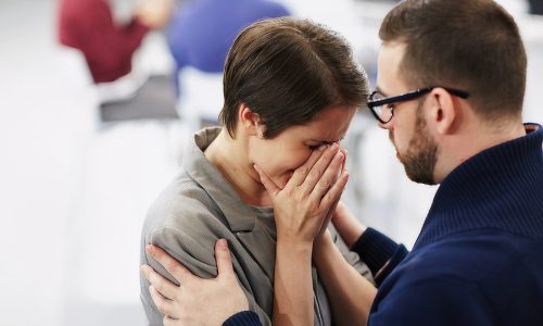 Helpful man reassuring upset woman at course of psychological support